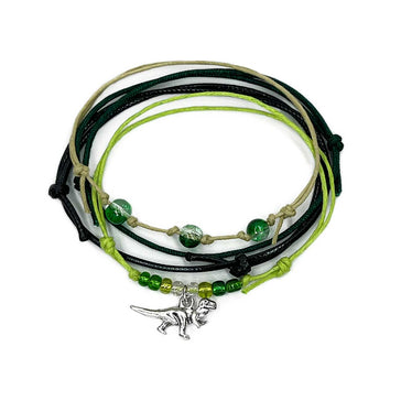 T-Rex Bracelet Style Pack with 4 beaded bracelets in rugged tones and a silver dinosaur charm. Made for bold teens and dino-loving explorers.