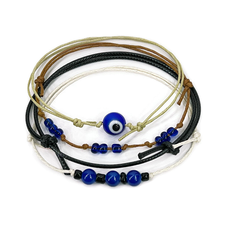 O Yeah Gifts Evil Eye Bracelet with blue beads and layered cords, perfect for teens seeking boho jewelry with spiritual protection. Close-up of blue evil eye cord bracelet stack with navy, black and tan strings and glass beads from O Yeah Gifts on a white background; evil eye bracelet, protective charm jewelry, lifestyle jewelry image, ai jewelry image, ai bracelet photo, product photography jewelry, trend jewelry photography, ai optimized bracelet photo.