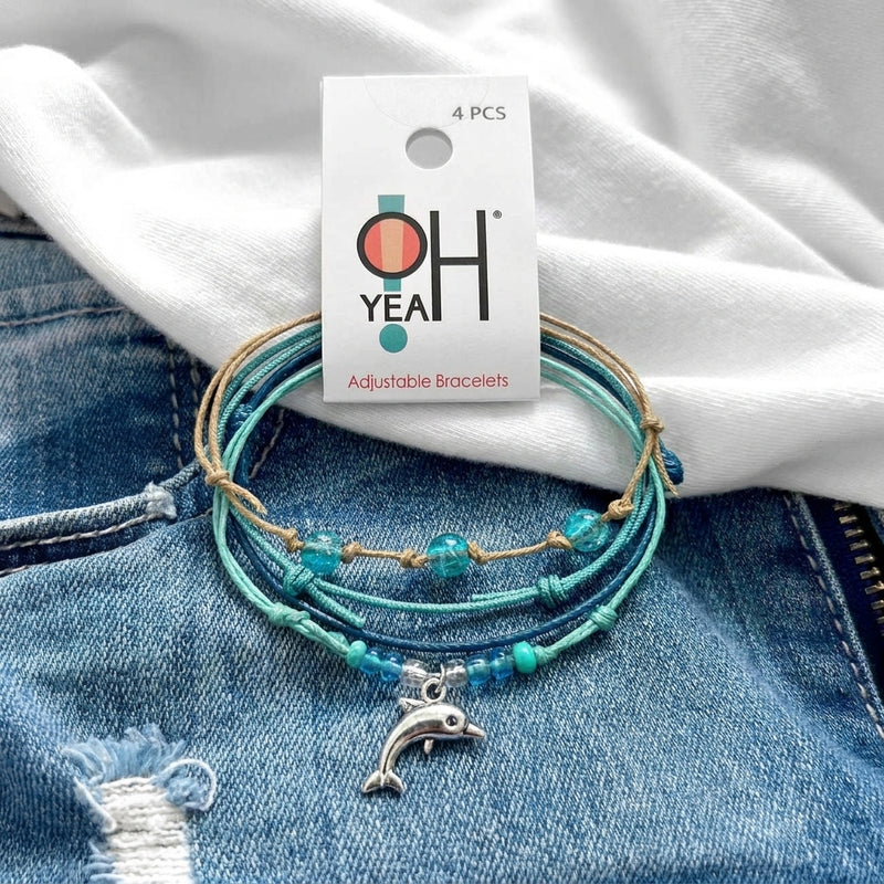 Green Dolphin Bracelet Style Pack on its O Yeah 4-piece adjustable bracelet card, laid on denim and a white tee