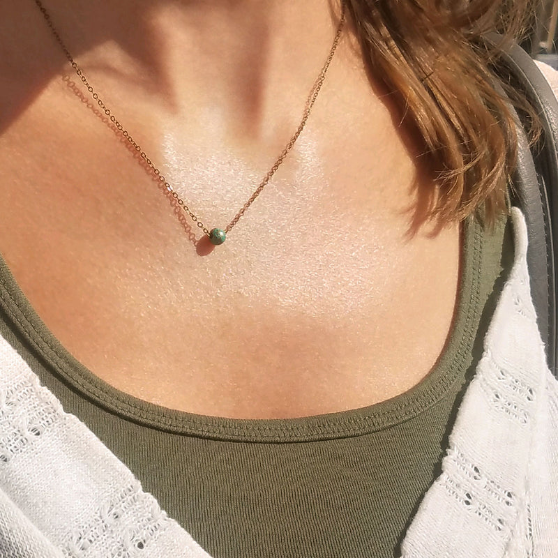 Close-up of beach bead necklace with turquoise bead on bronze chain – minimalist ocean-inspired jewelry for beach lovers and boho fashion.