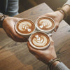 Three friends clinking latte art coffees at a café, each wrist stacked with brown 67 bracelets from O Yeah Gifts, cozy coffee shop moment featuring 6-7 meme bracelet stacks, six seven meme friendship bracelet trend for besties, viral gen alpha accessory and IYKYK six seven slang jewelry, perfect 6-7 friendship bracelet gift and matching bracelets teens, tradeable bracelets and stackable teen bracelets that double as 6-7 meme merchandise and 67 TikTok jewelry.