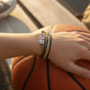 Hand resting on an orange basketball on outdoor bleachers, wearing layered tan and black 67 string bracelets from O Yeah Gifts, sporty 6-7 meme bracelet and viral gen alpha accessory for hoopers, six seven meme drip that pairs with new gen z slang, 67 trend bracelet as school safe bracelet and school friendly accessory for practice and games, six seven funny gift and 6-7 meme merchandise teens can trade as stackable teen bracelets and bestie bracelets.