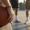 Close-up of a teen basketball player’s hand gripping a ball on the court, brown 67 bracelet visible on the wrist while teammates stand in the background, athletic 6-7 meme bracelet from O Yeah Gifts, six seven meme accessory that fits the 6-7 TikTok trend and gen alpha 6-7 culture, 67 trend jewelry for players who love inside jokes, school safe bracelet and viral bracelets for school, six seven funny gift and 6-7 meme merchandise for sports fans.
