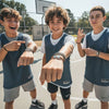 Three tween boys on an outdoor basketball court showing off their matching black and brown 67 string bracelets from O Yeah Gifts, lifestyle jewelry image and ai bracelet photo style of a 6-7 meme bracelet that has friends asking what is 6 7 and what does 67 mean, perfect 67 trend bracelet and school safe friendship bracelet gift for gen alpha hoopers.