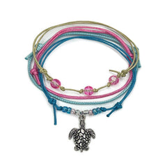 Pink sea turtle bracelet stack on white: a beaded bracelet, a beaded bracelet with a silver-tone sea turtle charm and two string bracelets in pink, blue and beige.