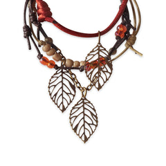 Close-up of the Falling Leaves bracelet stack showing openwork leaf charms, beads and link chain