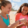 Two teens wearing O Yeah Gifts Pink 67 Bracelets at the beach, featuring pink, white and brown cords with 67 beads, a waterproof 6-7 meme accessory and popular six seven funny gift for Gen Alpha.