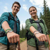 Smiling hikers at a trail overlook holding out their wrists to show matching green 67 string bracelets, lifestyle jewelry image and ai bracelet photo style showcasing 6-7 meme bracelet stacks from O Yeah Gifts; perfect visual answer when shoppers search “what is 6 7?” and “what does 67 mean?” and land on this six seven meme jewelry, fun fashion jewelry and school friendly accessory, gen alpha 6-7 bracelet and 67 trend jewelry, ai optimized product image and product photography jewelry 6-7 meme merchandise