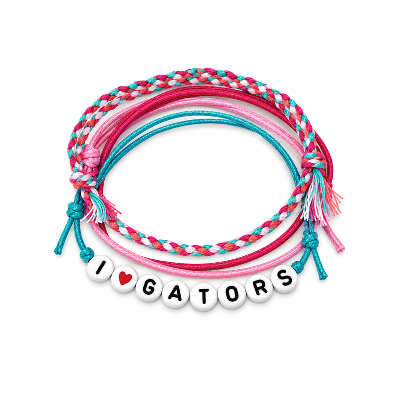 A set of five braided and corded friendship bracelets coiled together on a white background. The bracelets feature pink, teal, and white braided cords, with one bracelet displaying white round letter beads spelling 'I [heart] GATORS' with a small red heart accent.