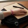 Teen wearing the O Yeah Gifts Pink 67 Bracelet Pack while studying, showing pink, white and brown waterproof string cords with white 67 beads. A school-safe 6-7 meme accessory and six seven slang bracelet trending as Gen Alpha 67 jewelry, viral friendship accessory and everyday teen fashion.
