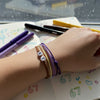 Tween wrist resting on a notebook with doodles of 67 and colorful pens scattered around, wearing stacked purple 67 bracelets from O Yeah Gifts, school friendly accessory and 6-7 meme bracelet perfect for class, six seven meme jewelry that turns homework into an IYKYK moment, 6-7 meme meaning TikTok and what does 6-7 mean written as doodles, viral gen alpha accessory and brain rot aesthetic, friendship bracelet trend and tradeable bracelets for besties, stackable teen bracelets and 67 TikTok jewelry 