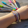 Close-up of a teen drawing with bright markers while wearing layered purple 67 bracelets, rainbow art supplies next to 6-7 meme bracelet stacks from O Yeah Gifts, school friendly accessory and viral bracelets for school, 6-7 meme accessory for teens and gen alpha funny slang bracelet, six seven meme jewelry tied to new gen z slang and 6-7 origin online, tradeable bracelets and stackable teen bracelets used as bestie bracelets, 6-7 friendship bracelet gift and 67 trend bracelet for the 6-7 TikTok trend.
