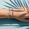 Purple 67 bracelet pack on a wrist resting by the edge of a sunny pool, soft shadows of palm leaves on a blue deck, aesthetic 6-7 meme bracelet and neon vibe bracelet style from O Yeah Gifts, gen alpha brain rot aesthetic turned into wearable 6-7 jewelry, six seven meme accessory and viral gen alpha accessory for summer, 67 trend bracelet and 6-7 meme drip, school safe bracelet and school friendly accessory when break is over, six seven funny gift, 6-7 meme merchandise and 67 TikTok jewelry for meme fans 