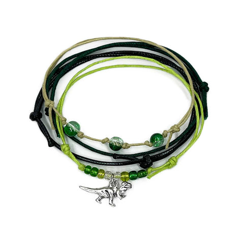 T-Rex Bracelet Style Pack with 4 beaded bracelets in rugged tones and a silver dinosaur charm. Made for bold teens and dino-loving explorers.