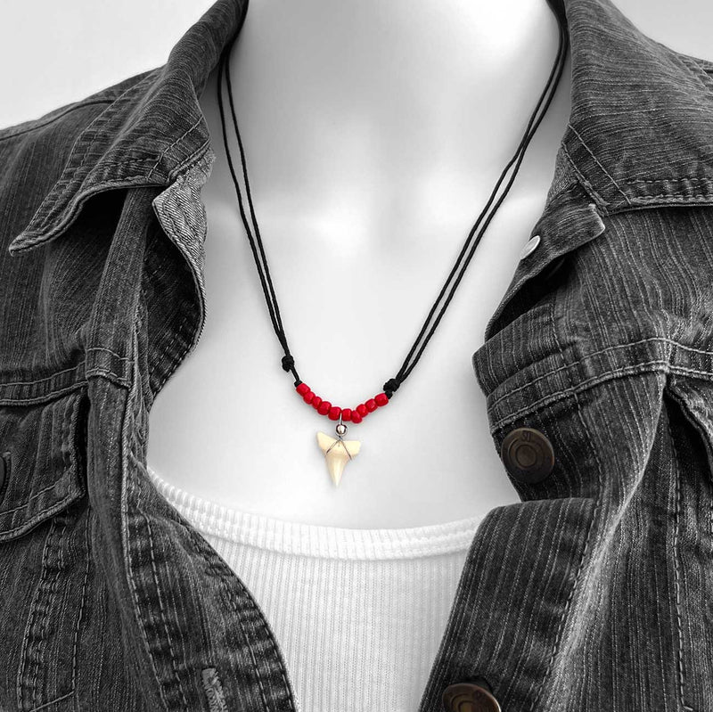 Red beaded shark tooth necklace with black cord, unisex surfer necklace featuring real shark tooth pendant, displayed on model with white tank and denim jacket