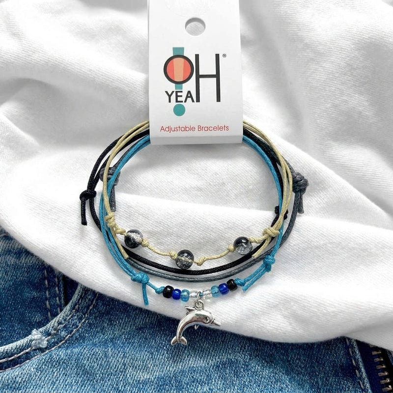 Black Dolphin Bracelet Style Pack on its O Yeah adjustable bracelet card, laid on a white tee and denim