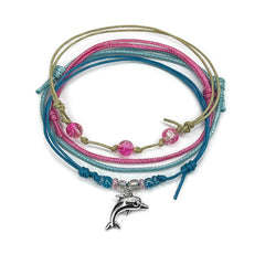 Pink dolphin bracelet stack on white: four adjustable string bracelets in pink, blue and beige with a silver dolphin charm.