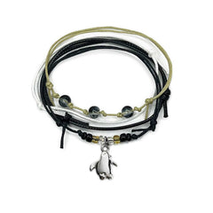Black penguin bracelet stack on white: 4 adjustable string bracelets in black, white, beige with a silver-tone penguin charm.