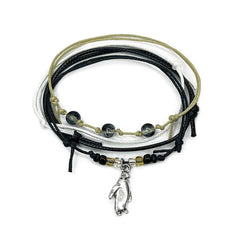 Penguin Bracelet Style Pack: 4 black, white and beige bracelets with a silver-tone penguin charm, flat lay on white