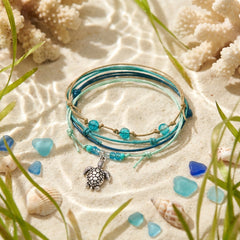 Green Sea Turtle Bracelet Style Pack on rippled sand with sea glass, coral, shells and sea grass