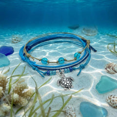 Blue Sea Turtle Bracelet Style Pack on the sandy sea floor in clear shallow water with sea glass, shells and coral