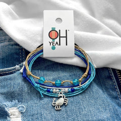 Crab Bracelet Style Pack on its O Yeah four-piece hang tag, laid on denim and a white tee.