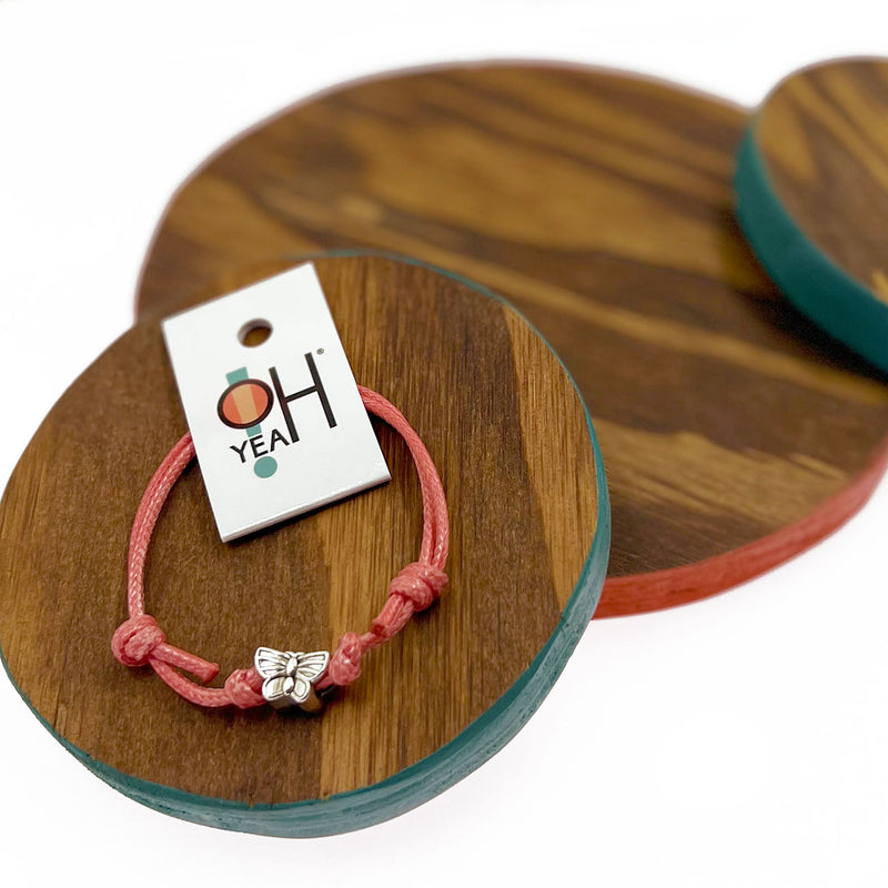 O Yeah Gifts Butterfly Charm Bracelet – Display of pink cord bracelet with a silver butterfly charm, perfect for adding a whimsical touch to your style.