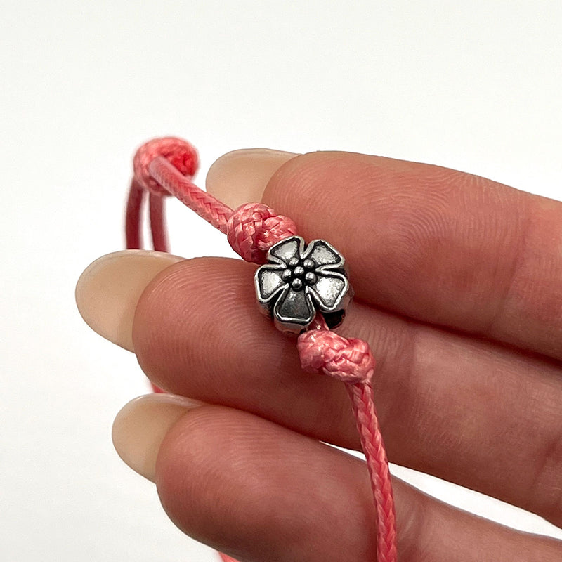 O Yeah Gifts Flower Bracelet – Closeup of the pink cord bracelet with a silver flower charm, capturing the playful and sweet style of floral-inspired jewelry.