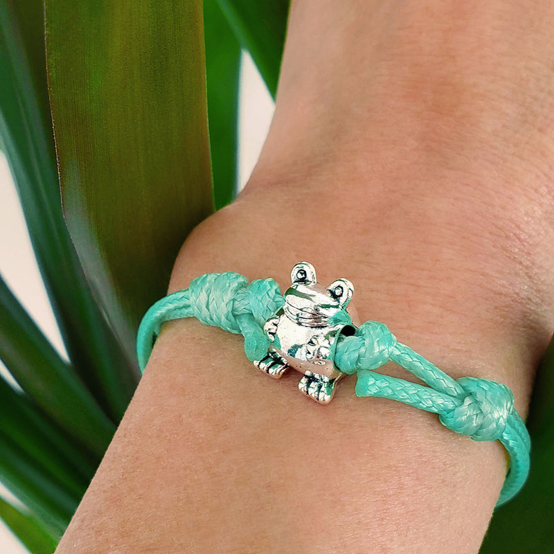 O Yeah Gifts Frog Charm Bracelet – Wrist shot featuring a green cord bracelet with a silver frog charm, perfect for adding a playful, nature-inspired touch to any outfit.