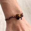 Close-up of tiger eye stone bracelet with brown cord – gemstone jewelry symbolizing courage and strength.