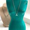 Whale Tail Necklace displayed on beach sand, capturing its seaside charm and natural vibes.